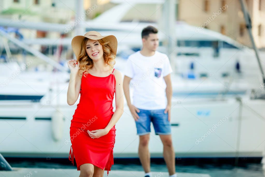 pregnant woman with husband posing outdoors on pier 