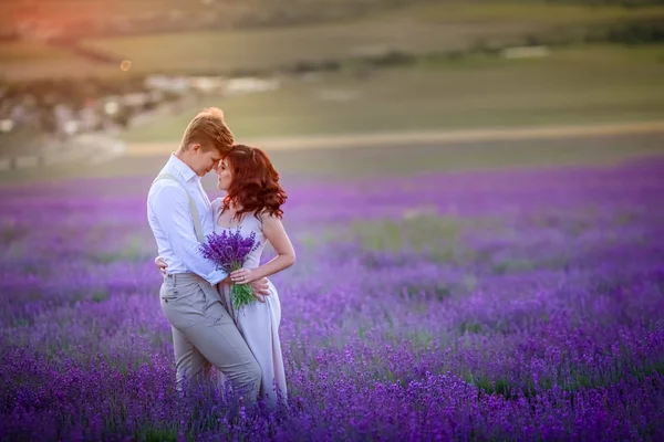 年轻情侣在阳光下摆在薰衣草领域的日落 — 图库照片