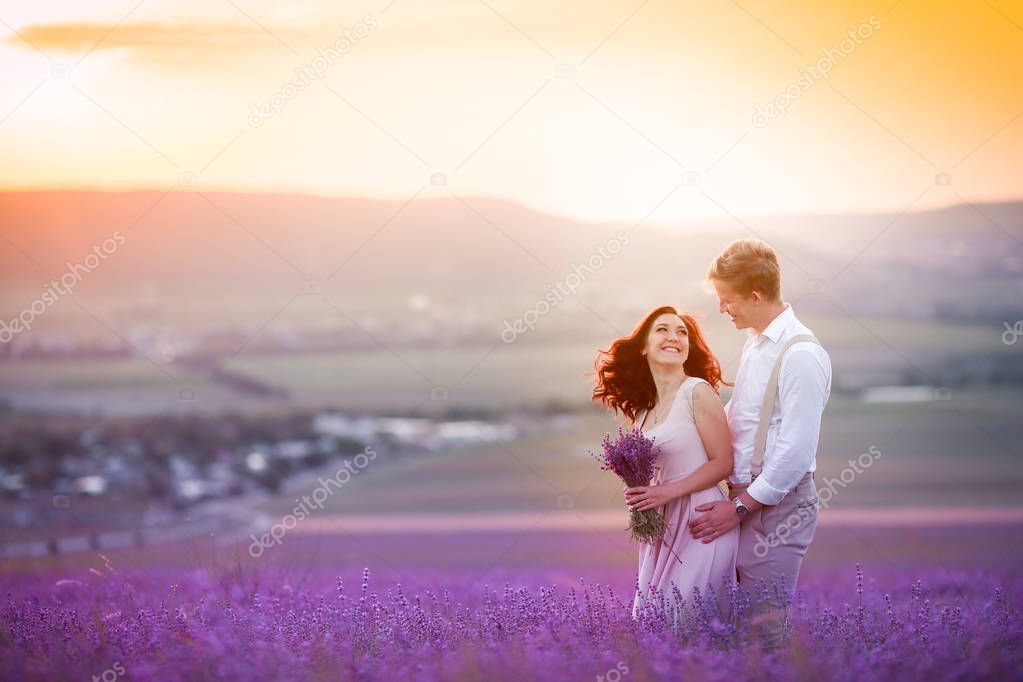 young beautiful couple on outdoor wedding photosession posing on the lavender field 