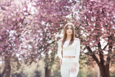 genç güzel kadın karşı çiçek açan ağaçlar poz 