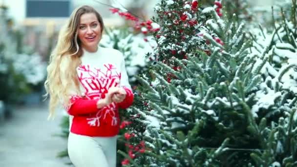 Uma menina em uma camisola de Natal vermelho brinca com neve — Vídeo de Stock