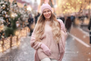 Pembe kazaklı bir kadın yeni yıl dekore edilmiş şehirde dolaşıyor.