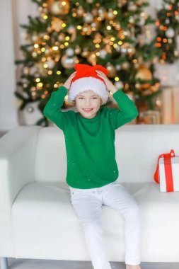 Yeni yıl arifesinde yalınayak beyaz pantolonlu çocuk kanepede yatıyor.