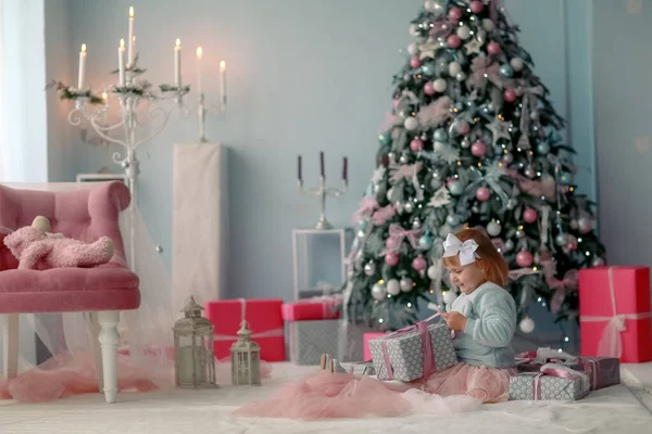 작은 소녀 가 바닥에 앉아 크리스마스 선물 상자를 여는 모습 — 스톡 사진