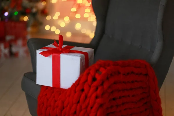 Chaise avec plaid chaud rouge et une boîte attachée avec ruban de Noël — Photo