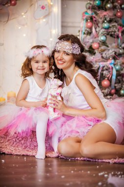 Göz kamaştırıcı anne-kız pembe kabarık bir etek giymiş Noel ağacının arka planında