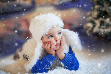 Bir gece köyünün arka planında kar yağışı sırasında çekilmiş bir çocuğun portresi.