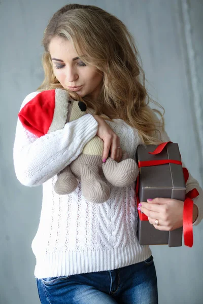 Közelkép egy nőről, aki mosolyog és egy dobozt tart egy ajándékkal és egy játékmacival. — Stock Fotó