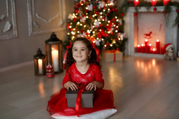 L'enfant tient Noël entre ses mains. cadeau sur le fond de la maison peinte nouvel arbre année — Photo