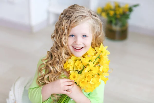 Curly menina de cabelos loiros no estúdio segurando um buquê de flores amarelas — Fotografia de Stock