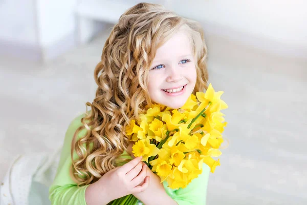 Menina sorridente da idade escolar com flores amarelas em suas mãos — Fotografia de Stock