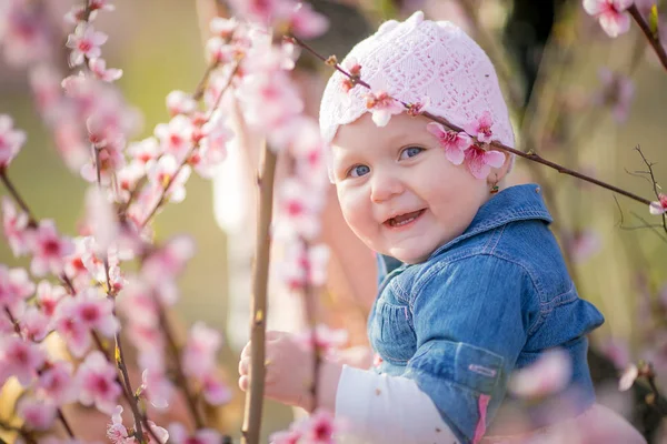 Detailní portrét 1-2-leté dívky venku v zahradě s růžovými květy na stromech — Stock fotografie