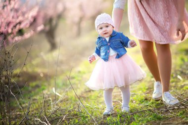 Çocuklu bir anne çiçek açan bahar ağaçlarının arasında yürür ve temiz hava solur.