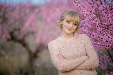 Doğadaki kadın, çiçekli parlak ağaç dallarının arka planına karşı