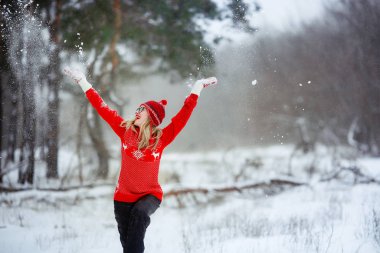 Kışın kırmızı kazaklı bir kadın karlı bir arazide hayatın tadını çıkarıyor.