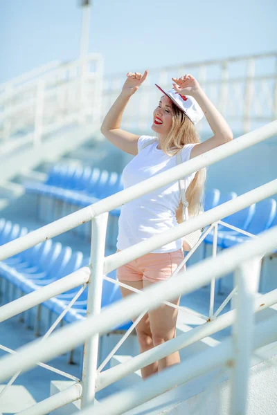 Eine Frau auf einem Sommersportpodium in kurzen Shorts mit nackten Beinen und einer Mütze auf dem Kopf — Stockfoto