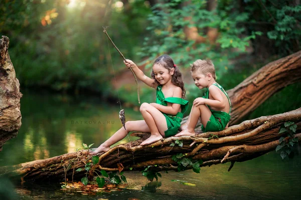 Chlapec a dívka děti 5-7 let sedí na kládě nad jezerem — Stock fotografie