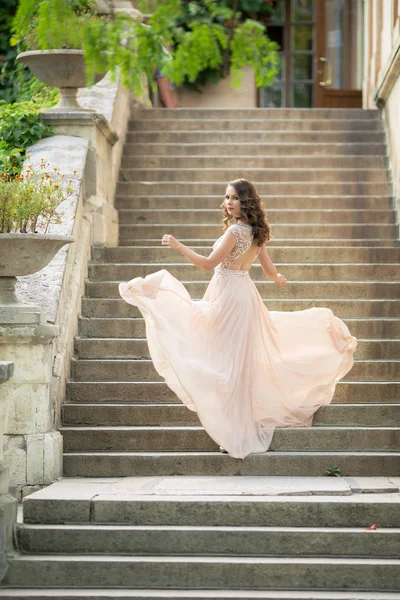 Vacker kvinna på bakgrunden av steg i en vacker bröllopsklänning i full tillväxt — Stockfoto