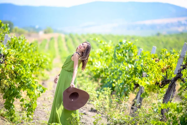 Giovane ragazza il proprietario del campo di uva cammina in un bel vestito elegante in estate sul campo di uva — Foto Stock