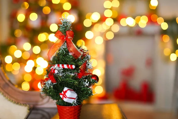 Pequeño árbol de Navidad artificial en el fondo de guirnaldas de color amarillo brillante y árbol de Navidad —  Fotos de Stock