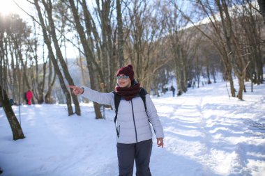 Gözlüklü bir kadın sıcak kıyafetler giyip gülümsüyor ve gülüyor.