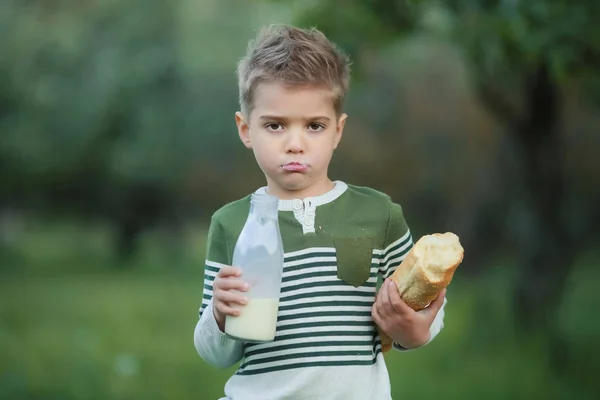 Niño con niña beber leche y comer un pan en un pajar en un pueblo al atardecer — Foto de Stock