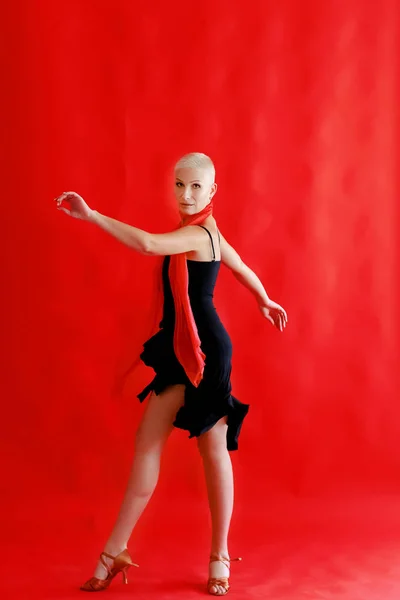 Woman 40 45 years old in a black dress dancing tango on a red background