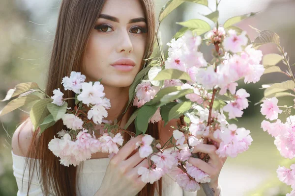 Porträtt av en vacker ung kvinna modell nära rosa grenar med Sakura blommor — Stockfoto