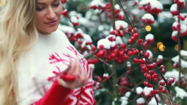 Chica en la calle en el fondo de los árboles de Navidad y bayas rojas — Vídeos de Stock