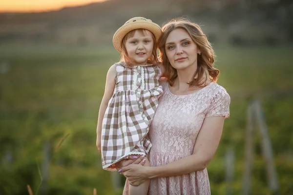 Мать с ребенком на руках стоит высоко в поле на закате с ребенком на руках — стоковое фото
