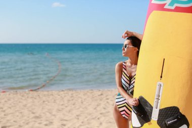 Okyanusun arka planında güneş gözlükleriyle kumlu bir sahilde güzel bir kadın.