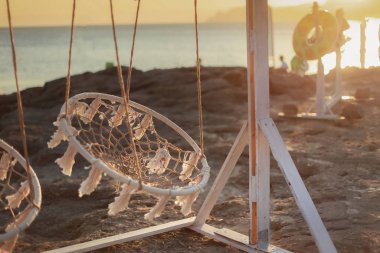 Sahilde gün batımının arka planında sallanıyor.