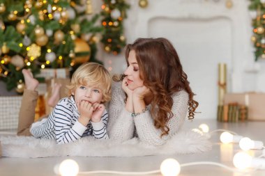 Anne ve oğlu evde Noel ağacının altında poz veriyorlar..