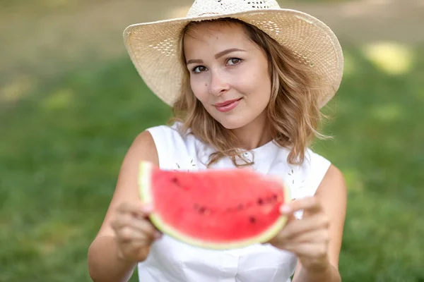Close-up of a woman with a watermelon in her hands on the background of green grass — Stock Photo, Image