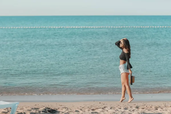 Egy nő egyedül a vad tengerparton, háttal a kamerának, a tengeri horizontot nézi. — Stock Fotó