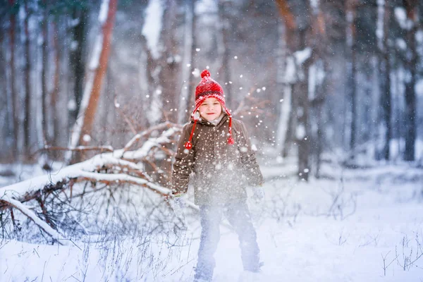 Un niño con ropa cálida de invierno camina sobre las corrientes de nieve cerca de árboles cubiertos de nieve — Foto de Stock