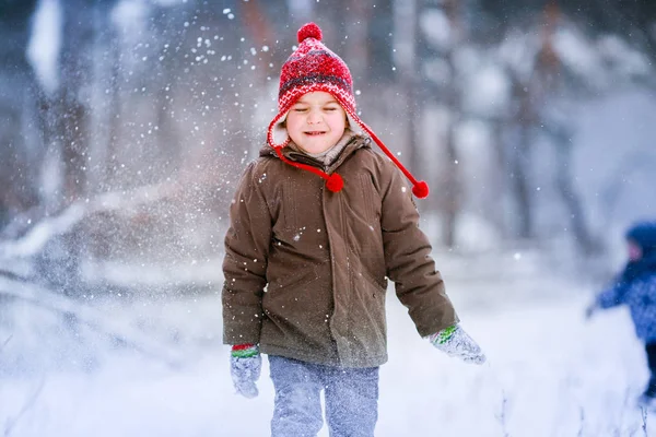 Un niño camina en un claro cubierto de nieve y se divierte en la nieve — Foto de Stock