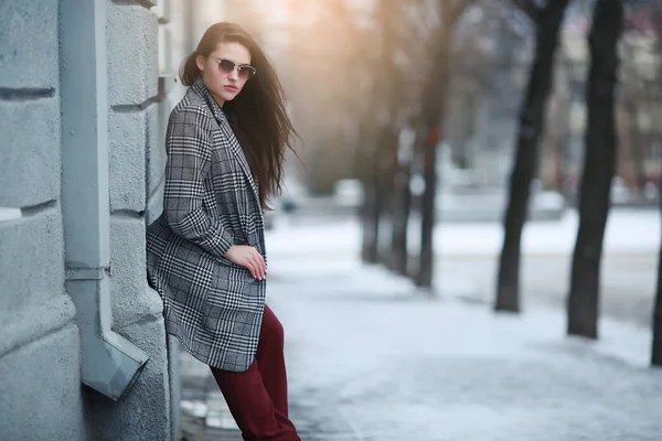 겨울에 한 여자가 흰 벽으로 둘러싸인 건물 근처에서 있다 — 스톡 사진