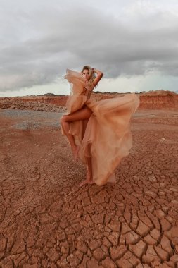 Çölde bir kadın döner ve uzun bir elbiseyle dans eder.
