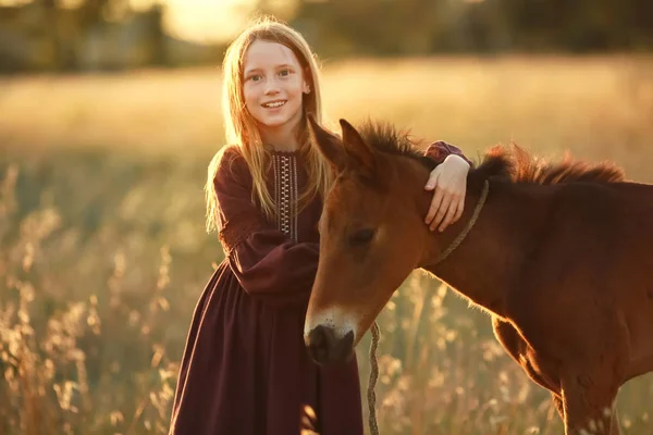 農家の娘が黄色の草原を馬で歩く — ストック写真
