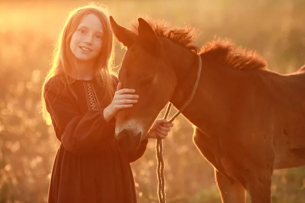 Ung kvinna utomhus i klänning och barfota petting sällskapsdjur häst — Stockfoto