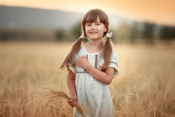 A pretty 9-year-old girl is standing in a field in a rural area on a hot  summer day Stock Photo