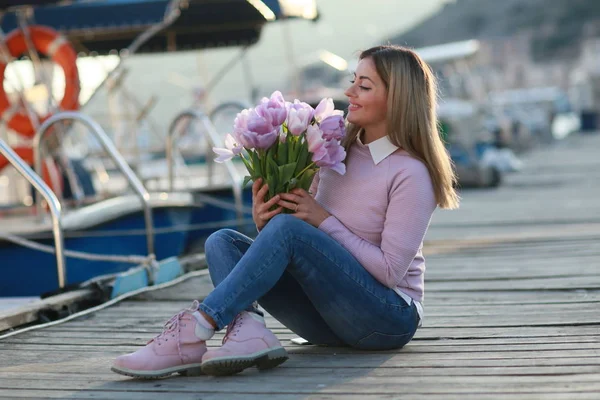 Eine junge und schöne Frau mit einem Blumenstrauß an der Küste — Stockfoto