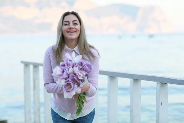 Frau in Nahaufnahme im rosafarbenen Pullover und einem Strauß Tulpen in den Händen — Stockfoto