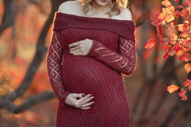 Kırmızı elbiseli hamile bir kadının göbeği.