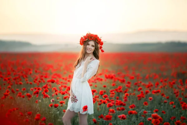 Eine Frau auf einem Feld mit einem Kranz auf dem Kopf aus roten Mohnblumen — Stockfoto