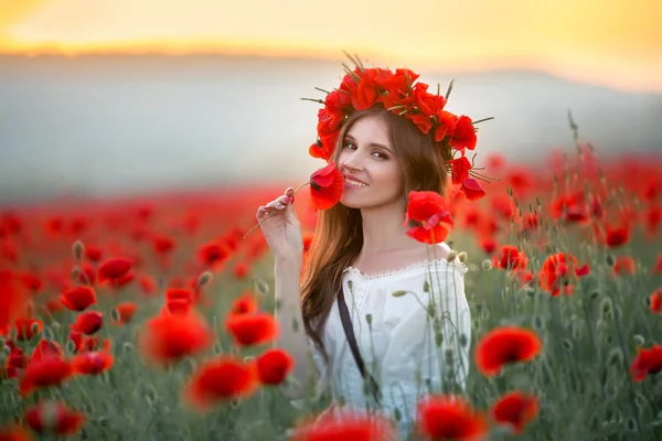 Eine Frau auf einem Feld mit einem Kranz auf dem Kopf aus roten Mohnblumen — Stockfoto