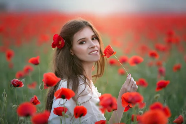 Een vrouw in een agrarisch veld met een krans op haar hoofd van rode papavers — Stockfoto