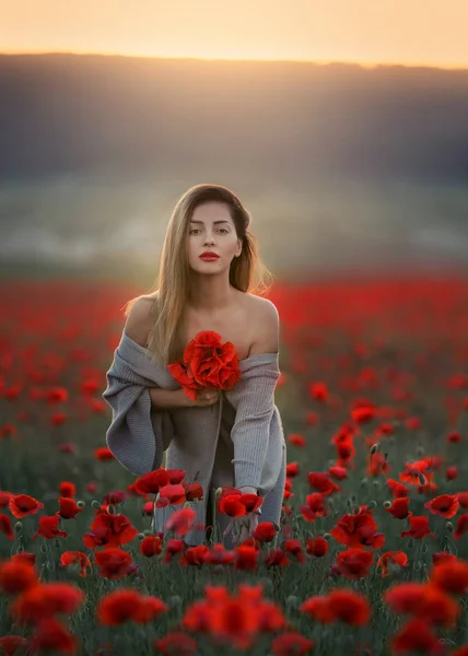 En vacker kvinna med bara axlar och en lång tröja på ett fält med vallmo — Stockfoto