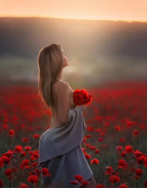 一个漂亮的女人，光着肩膀，穿着一件长长的毛衣，站在有罂粟的田里 — 图库照片
